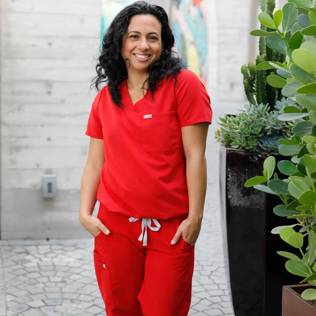 Tina smiling outdoors in red medical scrubs