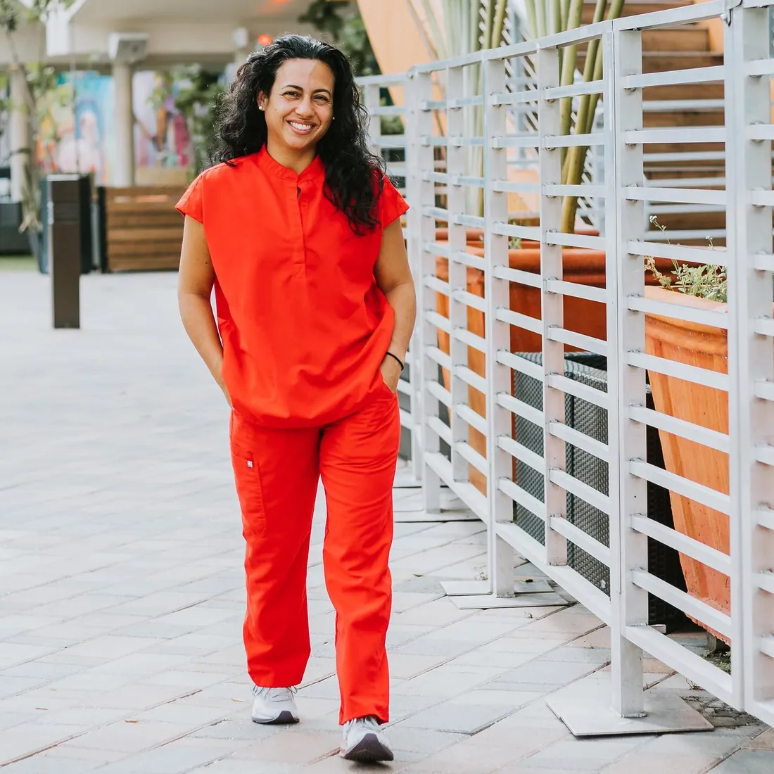 Tina walking outdoors in red clinical attire